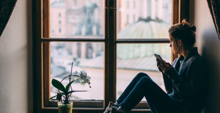 Young women sitting in bay window looking out on on the world