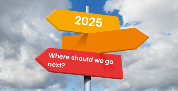 Multicoloured arrow-shaped road signs against a blue cloudy sky. The top sign has the year 2025 on it, and the bottom one reads 'where should we go next?'