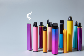 A group of colourful vapes arranged vertically. A smoke graphic hovers over the top of one.