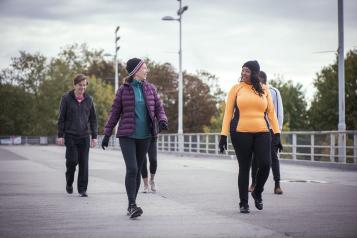 A group of mixed age people, including older people, walking down a road. They are dressed for cold weather. 